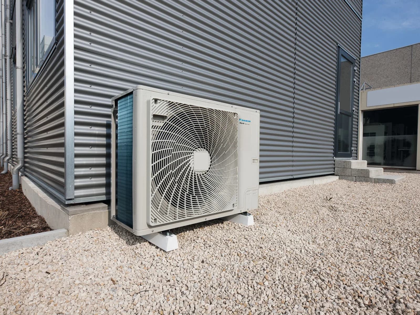 Daikin Sky Air RZAG-B Premium buitendeel geïnstalleerd naast een modern bedrijfspand — voor kantoor en winkel
